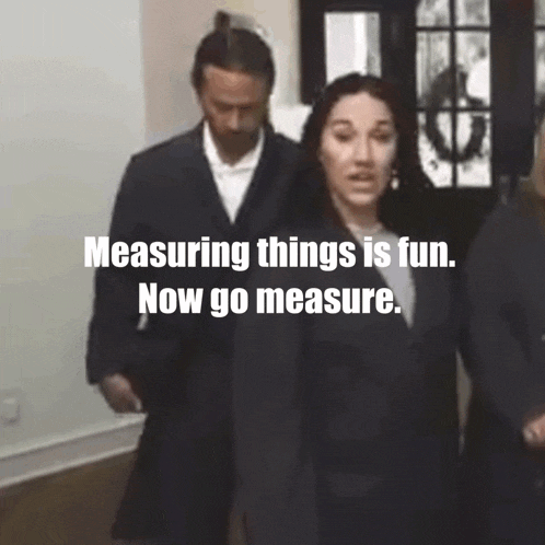 A GIF of a woman and a men, the woman holding a measuring tape and intensely looking in the camera, saying 'Measuring things is fun. Now go measure.'